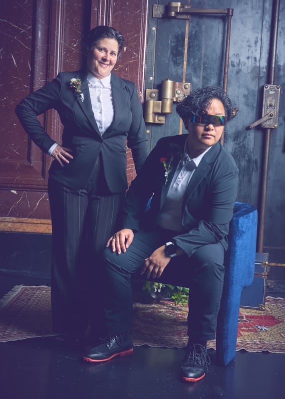 Holly and Rosalie in dark suits at a blue door