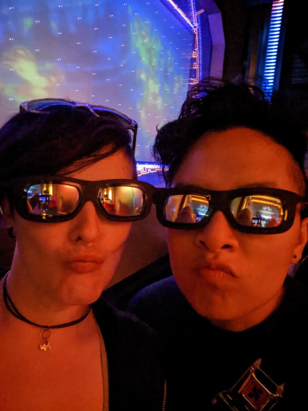 Holly and Rosalie in sunglasses under blue and orange lights