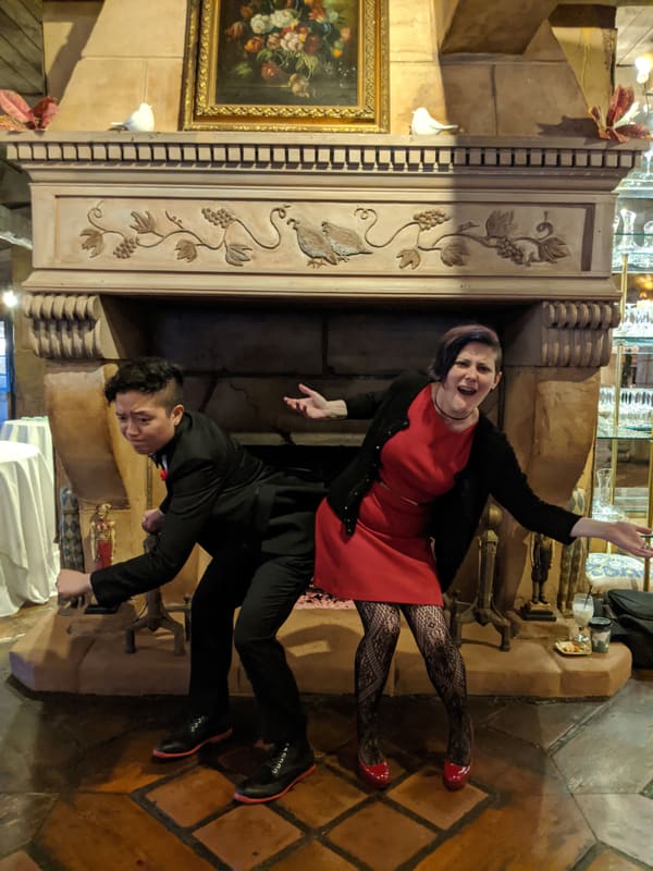Holly and Rosalie goofing around in front of an ornate fireplace
