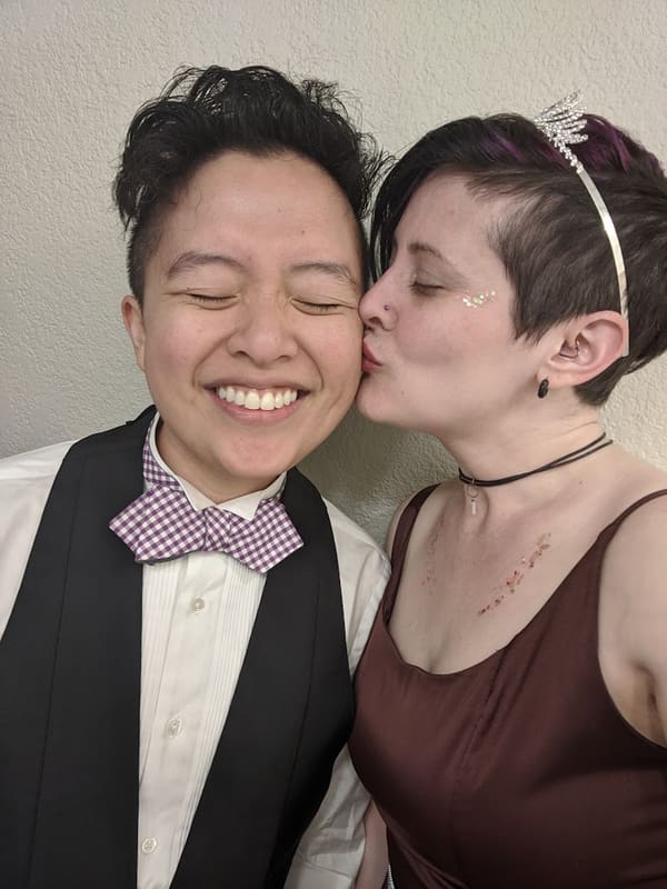 Rosalie in a gingham bow tie kissing Holly on the cheek