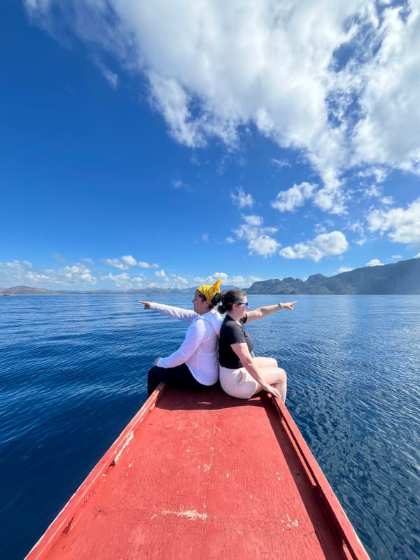 Holly and Rosalie on the red bow of a boat on open water
