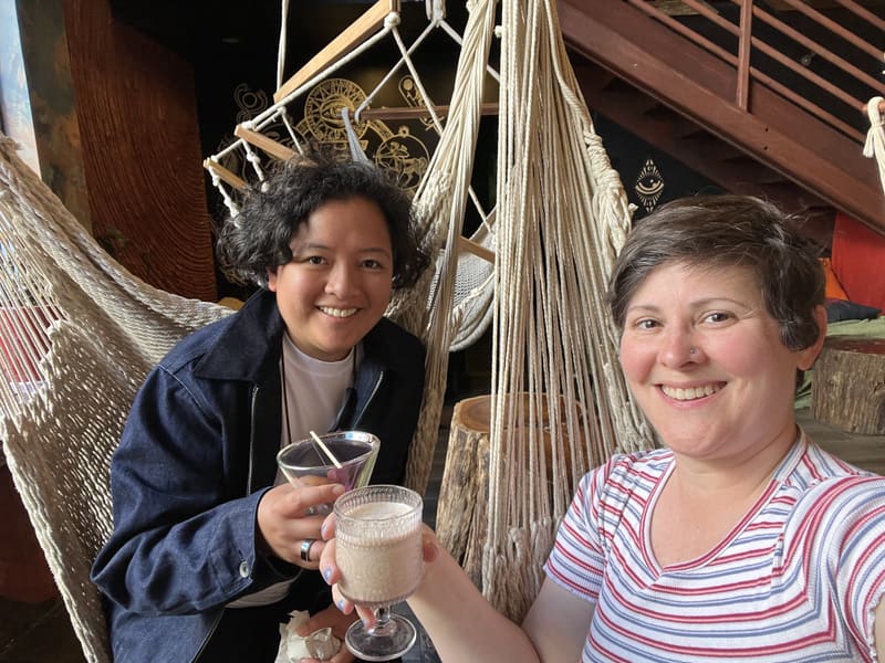 Holly and Rosalie raising drinks in front of hammocks